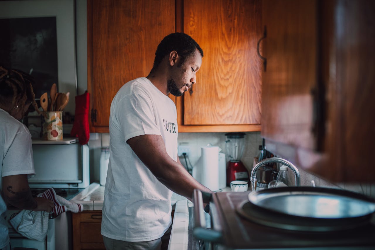 A man and woman volunteer wash dishes in a kitchen, helping their community.